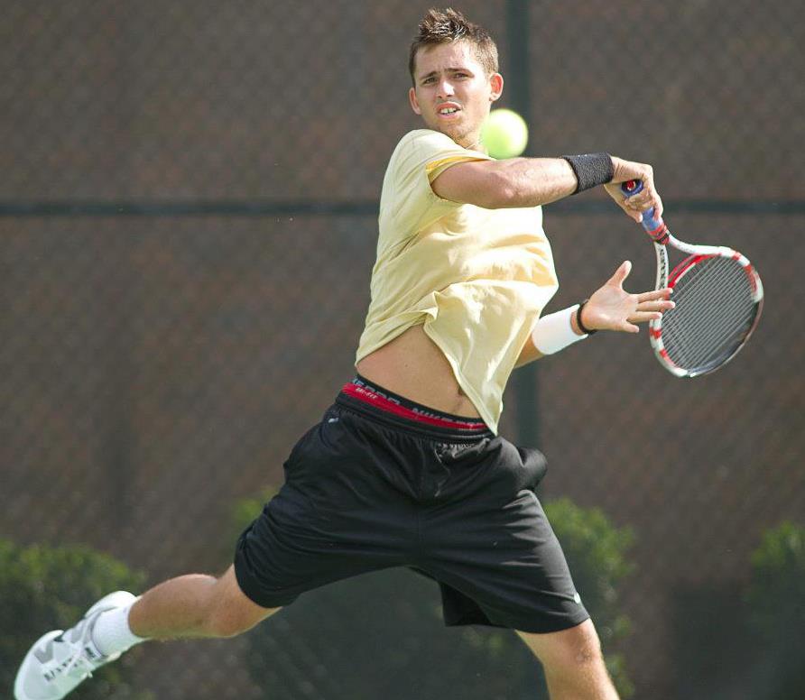 A tennis player in mid-air hits a forehand shot with a racquet on an outdoor court.