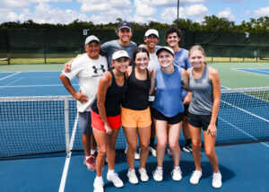Group of tennis players posing on court