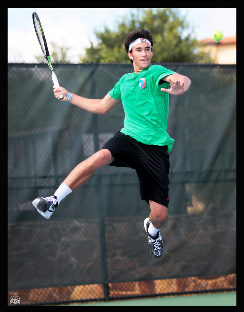 A tennis player in a green shirt jumps to hit a forehand shot on an outdoor court.