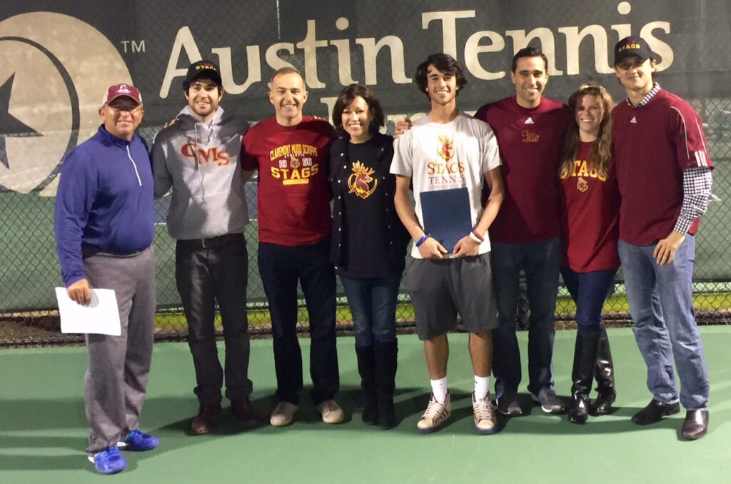Eight people stand together on a tennis court in front of an Austin Tennis sign, smiling for a group photo.