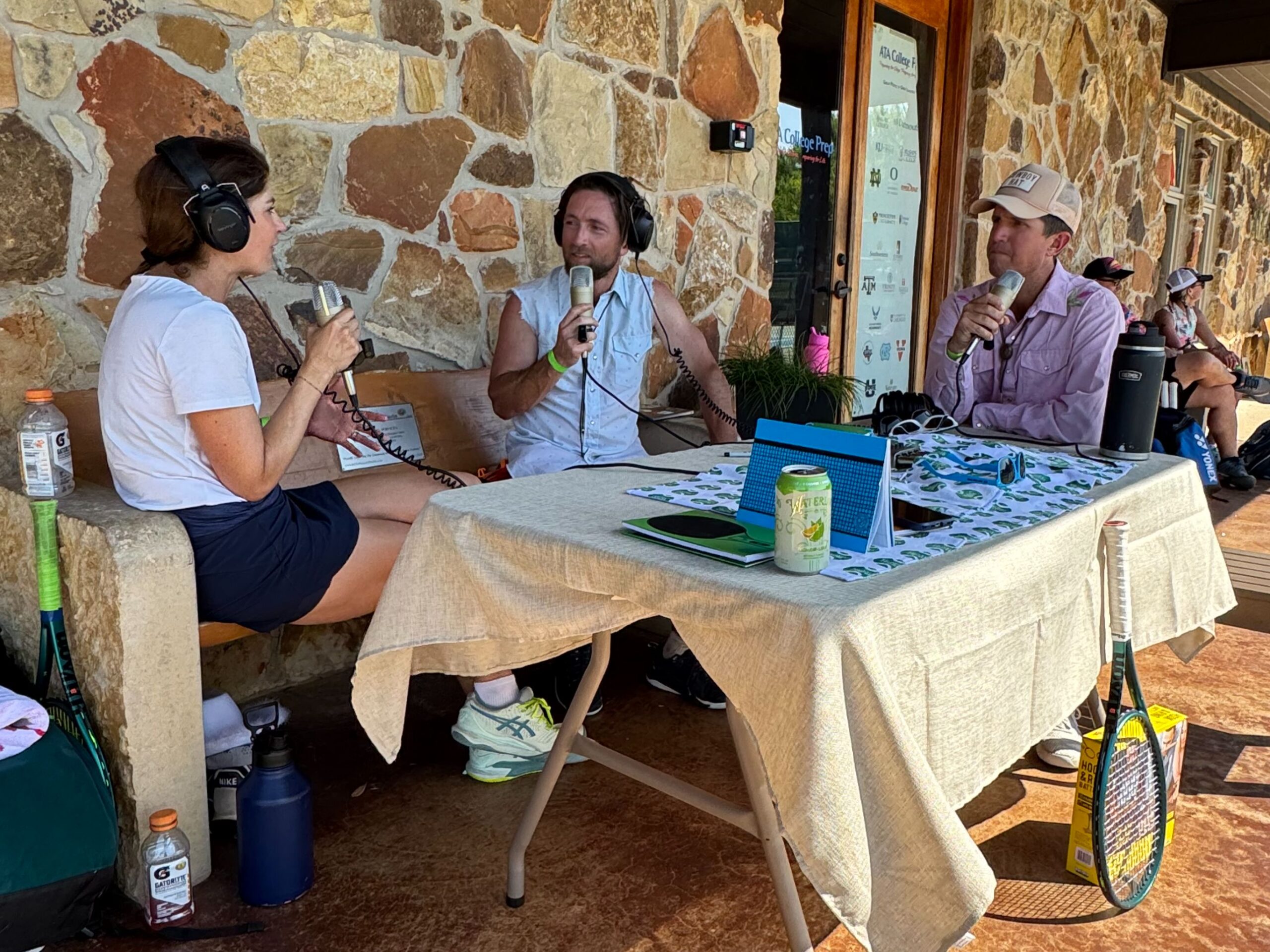 Three people recording podcast outside stone building