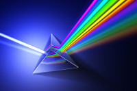 A glass prism dispersing white light into a rainbow spectrum on a dark blue background.
