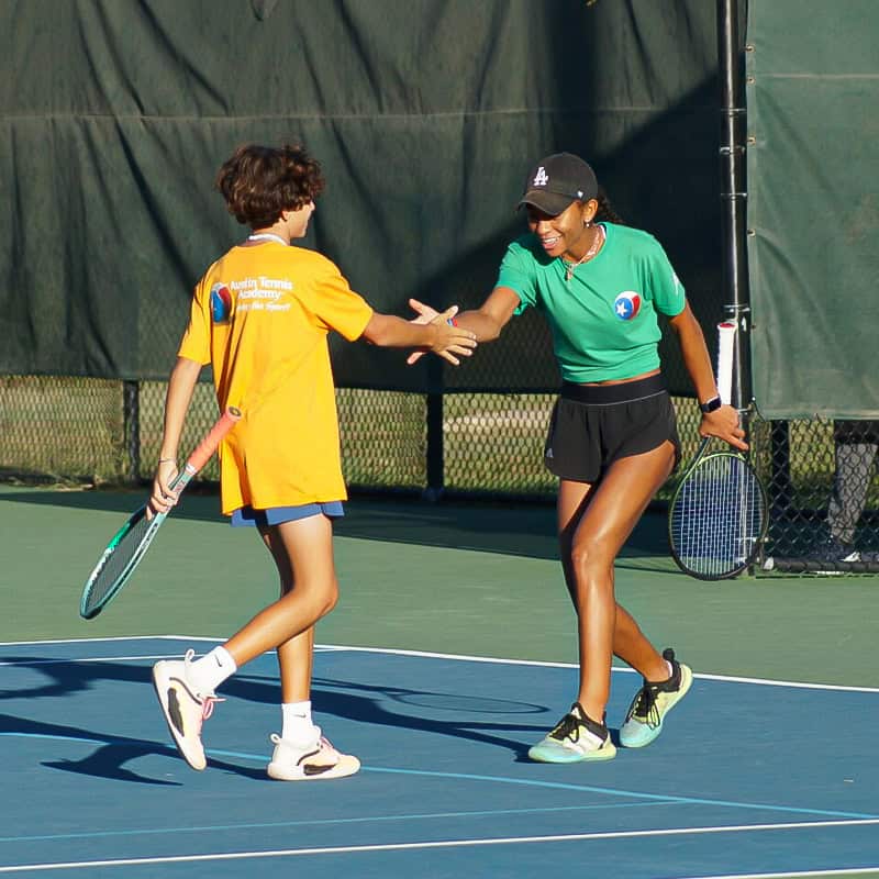 Tennis coach and child high-five on court